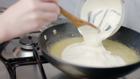 Adding heavy cream into a preheated pan, and frying in 4K. Stock Footage 138067288