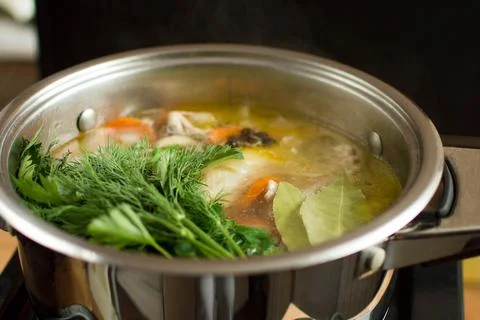 Adding herbs, bay leaves and seasonings to the broth Stock Photos