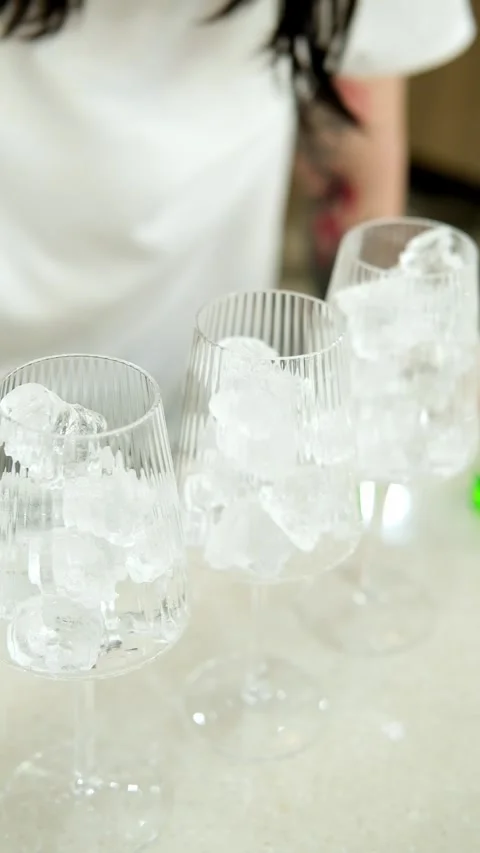 Adding ice cubes in empty glass. Making a fresh drink on the counter. Stock Footage 307273626