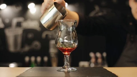 Adding ice cubes into a glass with strawberry syrup and mint 库存影片 113950800