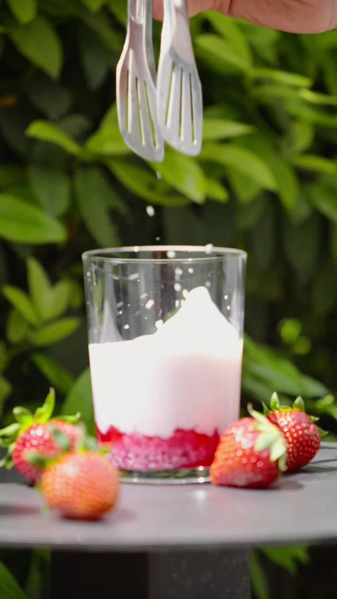 Adding Ice Cubes to Glass with Strawberry Milk Vídeo Stock 338447862