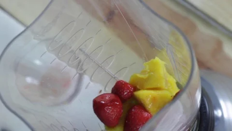 Adding ice to the strawberry-mango mix to make a smoothie 스톡 동영상 130062896