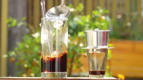 Adding Ice to Traditional Vietnamese Black Coffee in Sunlight. 스톡 동영상 333589721