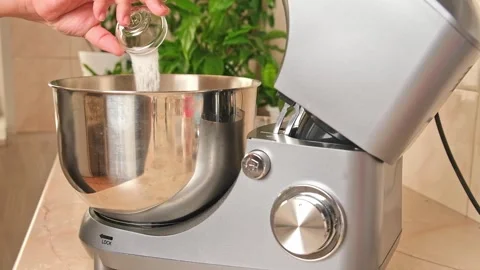 Adding ingredients to metal bowl of planetary mixer and mixing. Preparation of Stock Footage 244803510