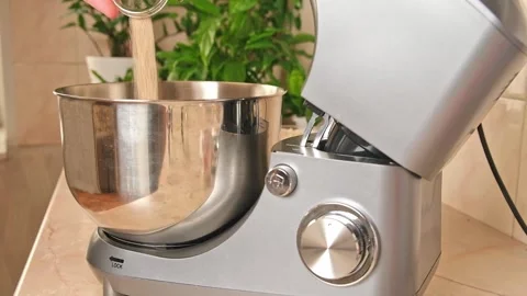 Adding ingredients to metal bowl of planetary mixer and mixing. Preparation of Stock Footage 245657243