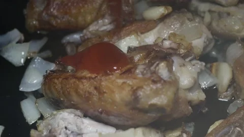 Adding ketchup to chicken wings with chopped onion and garlic fried in a pan Stock-Footage 225241485