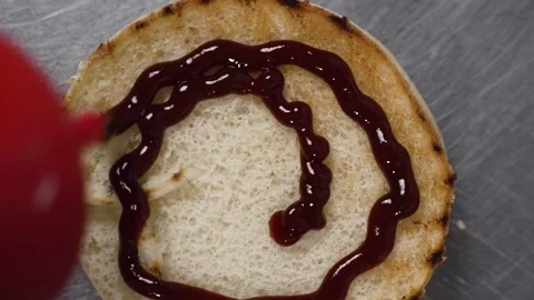 Adding ketchup while cooking hamburger Stock Footage 297004160