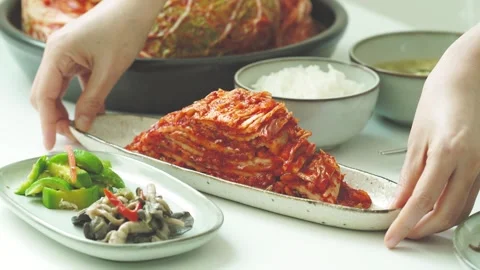 Adding Kimchi to Traditional Korean Meal Table Stock Footage 334699229