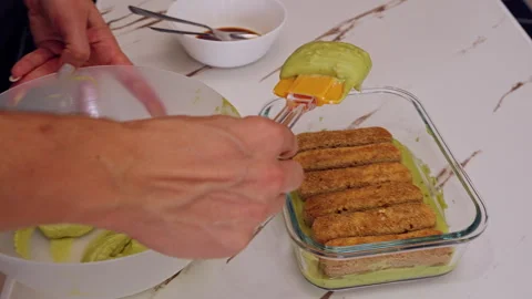 Adding Layer Of Savoiardi Biscuits Into Glass Dish With Green Cream Using Spatul Stock Footage 326638195