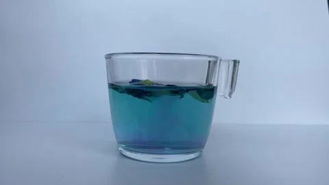 Adding lemon to butterfly pea flower tea Stock Footage 295493750
