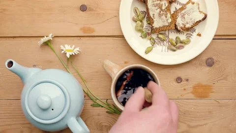 Adding lemon to hibiscus tea.  Served with ginger cake and pistachios Stock-Footage 156451288