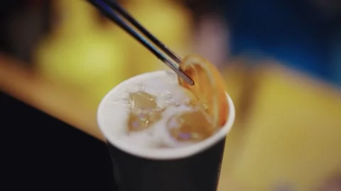 Adding a lemon slice to an iced drink cocktail in a bar setting, capturing a  Video stock 292668559