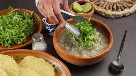 Adding lettuce to a plate of white pozole, September national holidays in Mexico Stock Footage 279210978