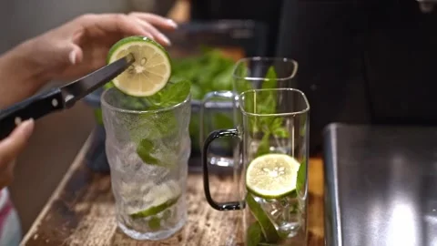 Adding lime slice to cocktail, bartender preparing vibrant drink with mint and Stock Footage 300678561