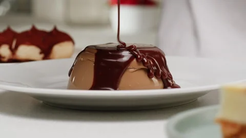 Adding liquid chocolate on cacao chocolate dessert panna cotta on plate close-up Stock Footage 279186773