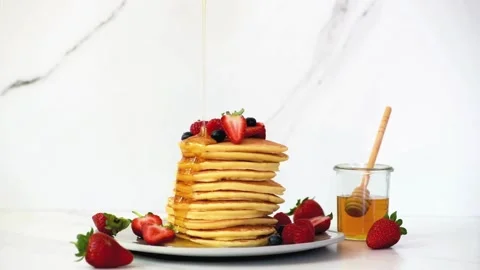 Adding maple syrup and fresh mix berries to pancakes. Stock-Footage 336589342