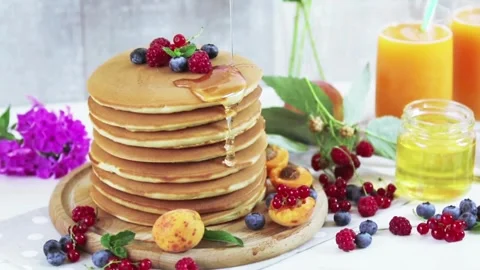 Adding maple syrup and fresh mix berries to pancakes. Stock-Footage 336589348
