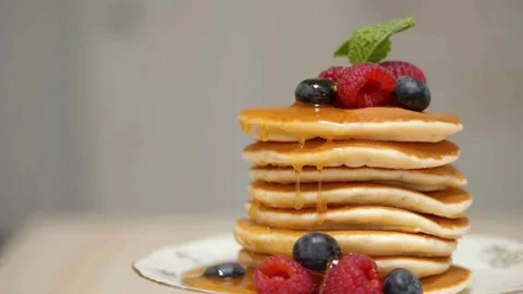 Adding maple syrup and fresh mix berries to pancakes. Stock-Footage 336589353