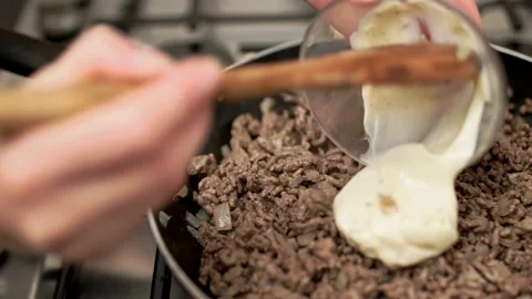 Adding mayo in a preheated frying pan with chopped onion and ground beef. Stock Footage 135461968