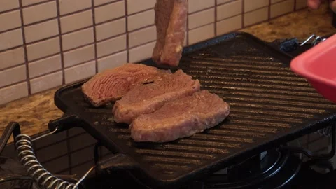 Adding meat to a hot grill with a big fork Stock Footage 130267229