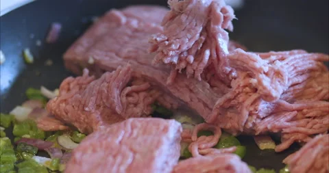 Adding meat to hot vegetables in frying pan Stock Footage 155546293