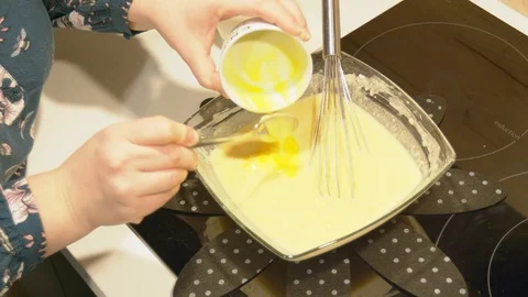 Adding melted butter and mixing the French pancake batter. Video stock 102401279