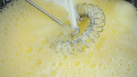 Adding milk to beaten egg with sugar to make a thin pancake batter. Stock Footage 274463103