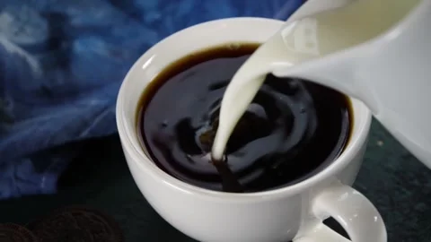 Adding milk in black coffee Stock Footage 169587366