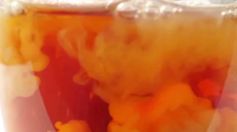 Adding milk to black tea in a glass mug, extreme close up Stock Footage 55470655
