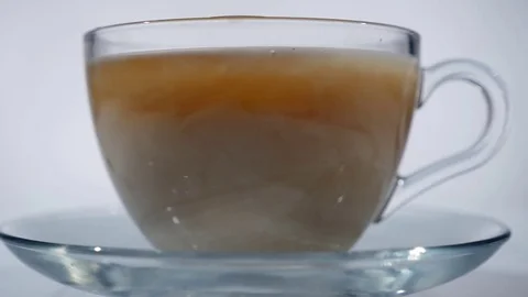 Adding milk to black tea in a glass mug, close up Stock Footage 75281787
