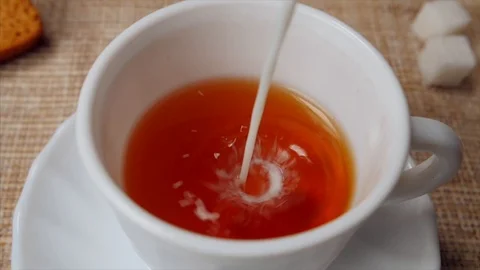 Adding milk in a black tea using tea-pot Stock Footage 113382569