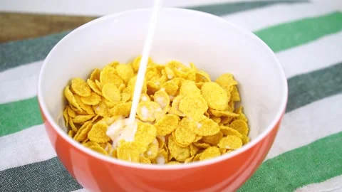 Adding milk to the corn flakes in a bowl Stock Footage 137536193
