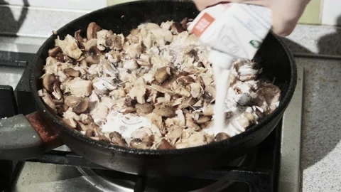 Adding Milk Cream to Fried Mushrooms in a Hot Pan at the Home Kitchen. Julienne Video stock 146756675