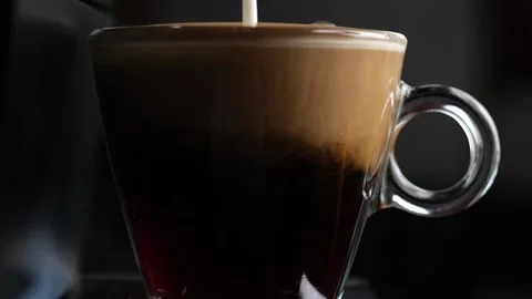Adding milk to a cup of black coffee in slow motion Stock-Footage 148141147