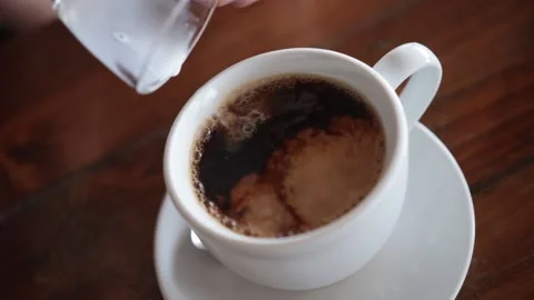 Adding milk to a cup of black coffee. White and brown swirling. Slow motion. Stock-Footage 233771781