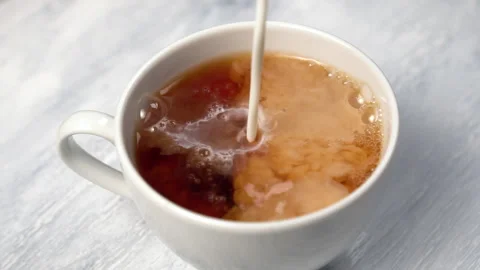 Adding milk to a cup of black tea Stock Footage