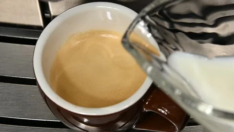 Adding milk to cup of espresso macchiato coffee Stock Footage 141994270