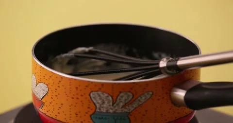 Adding milk to flour and butter in a pan and stirring 2 Stock Footage 132146346