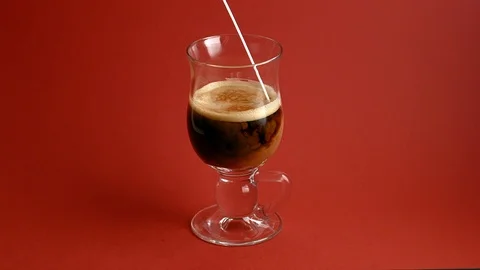 Adding milk to glass cup of coffee, red background Stock Footage 85590966