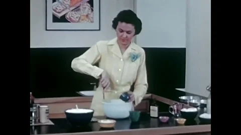 Adding milk, vanilla and eggs to cake mix in this archival cooking show from Stock Footage 75074908