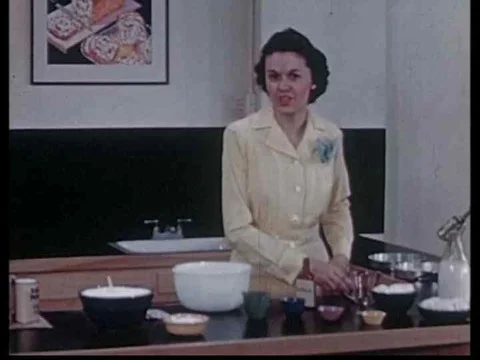Adding milk, vanilla and eggs to cake mix in this archival cooking show from Stock Footage 75097779