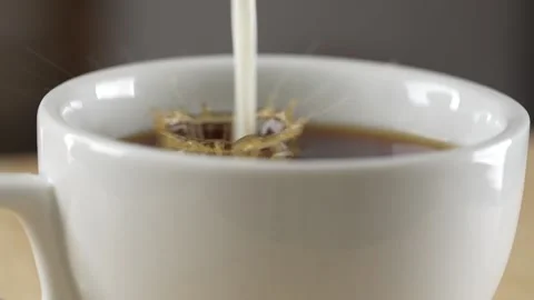 Adding milk to a white cup of black tea, rotation. Slow motion Stock Footage 172341938