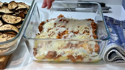 Adding minced grated cheese to the moussaka Stock Footage 219879008