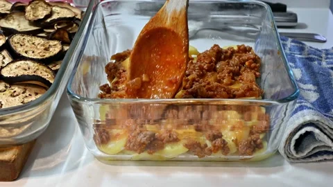 Adding the minced meat to the moussaka Stock Footage 219879084