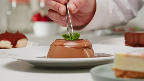 Adding mint decor on cacao chocolate dessert panna cotta on plate close-up Stock Footage 278919358