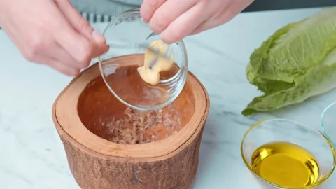 Adding mustard into a Caesar Salad Sauce mixture in a Mortar and pestle in 4K. Stock Footage 140766724