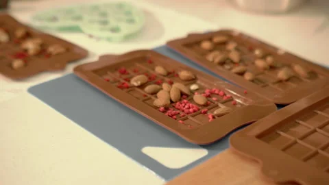 Adding nuts and dried strawberries to silicone molds to make homamade chocolate Stock Footage 202134169