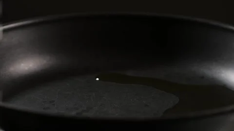 Adding an oil on black pan close-up. Chef going to cook food on a boiling pan Stock Footage 257083890