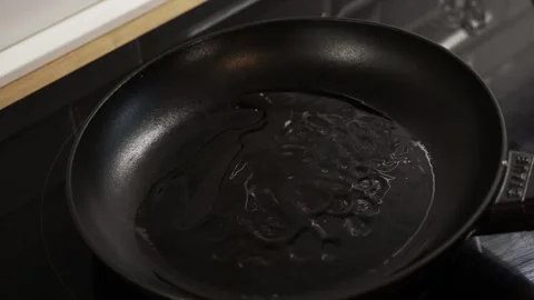 Adding oil into a hot pan after placing spiced chicken breasts for frying 動画素材 332826792