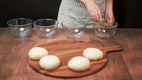 Adding olive oil and pizza dough in a glass bowl then covering with clear film Stock Footage 137429366